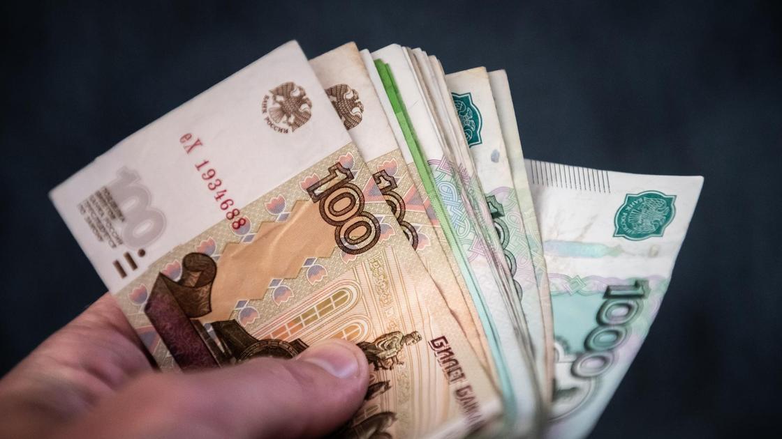 Мужчина держит в руках рублёвые банкноты