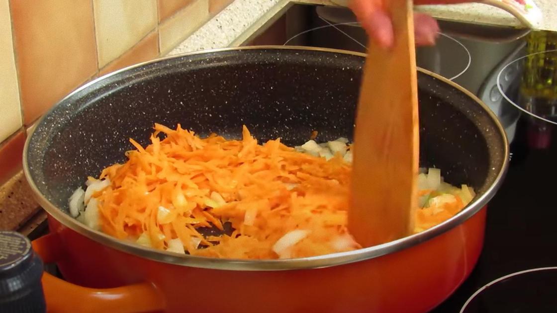 В сковороде лопаткой мешают тертую морковь и нарезанный лук
