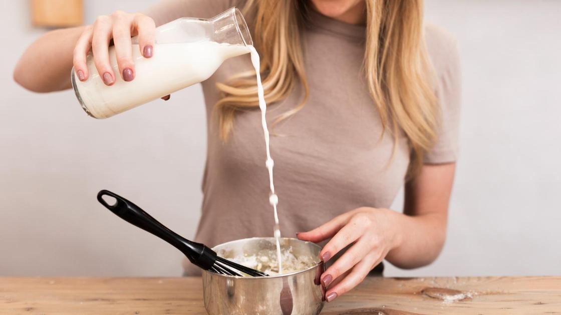 Девушка наливает молоко из бутылки в сотейник