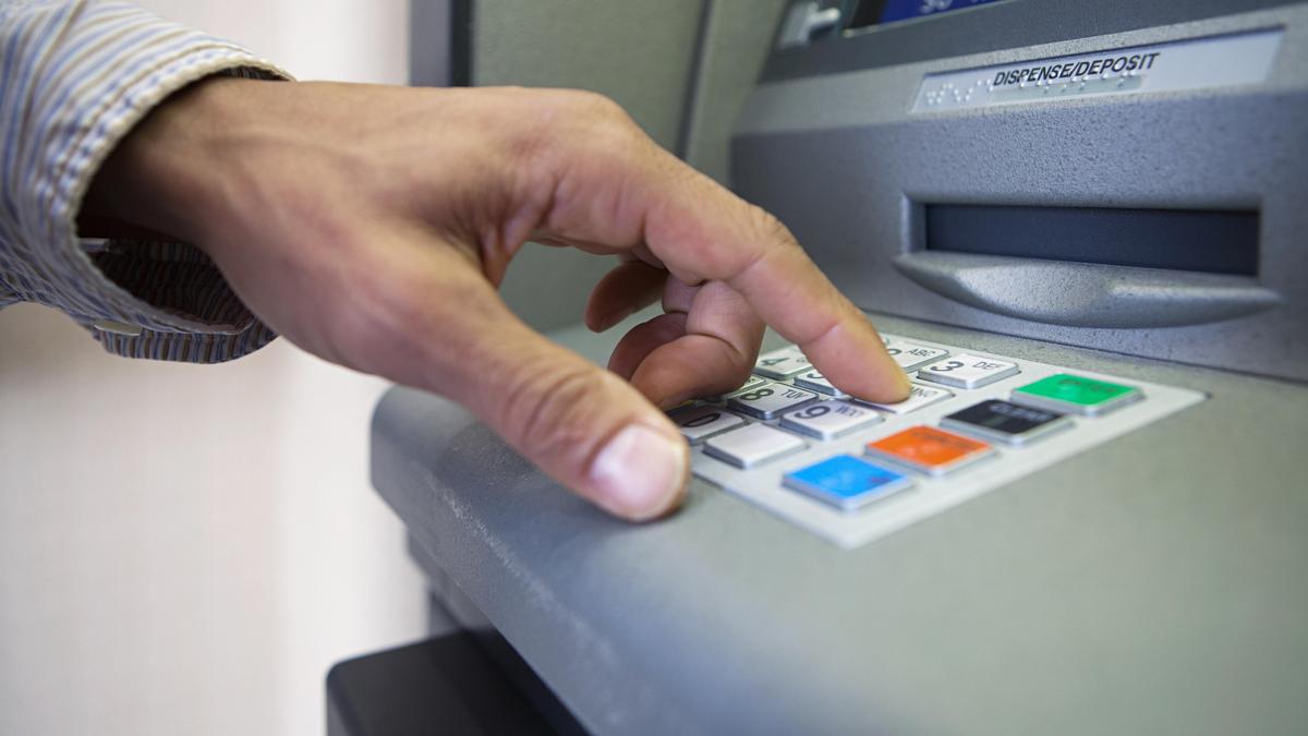 Мужчина набирает пин-код карты на банкомате