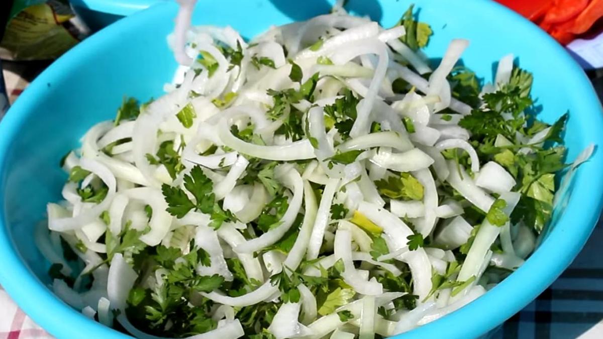 Нарезанные лук и зелень в пластиковой миске