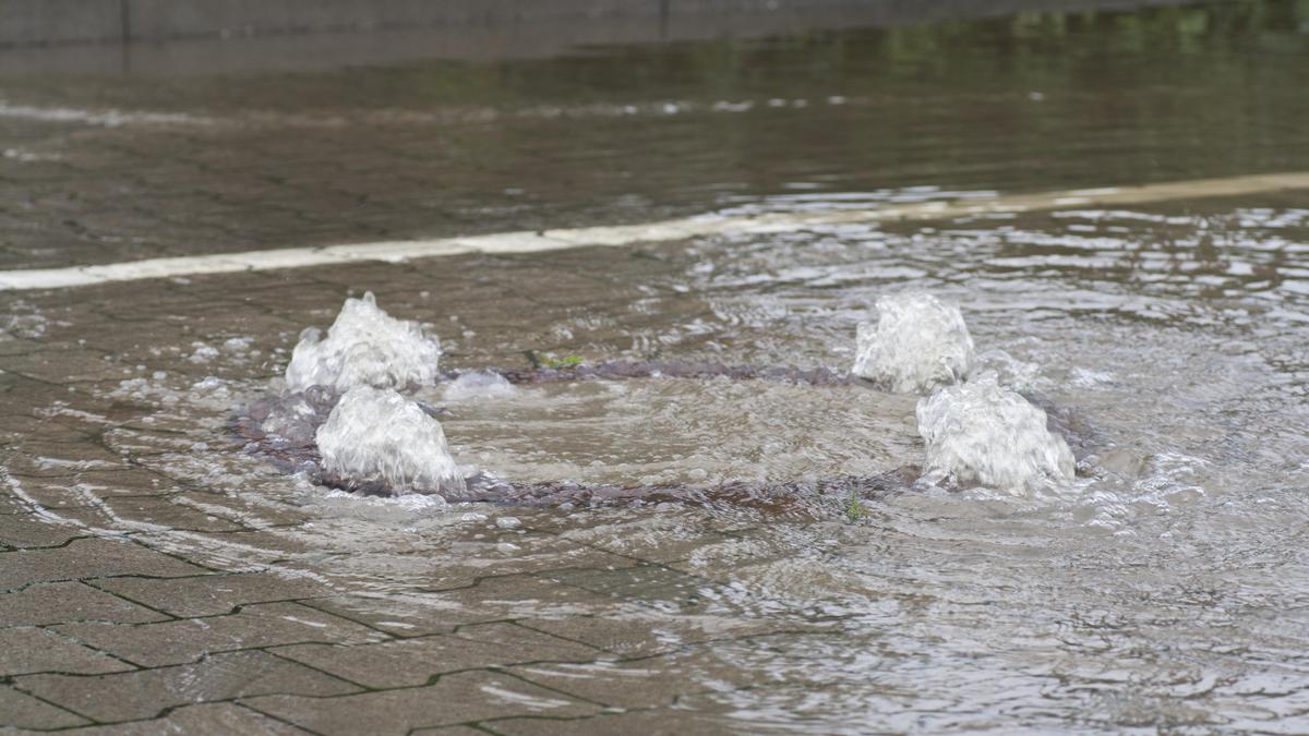 Вода вырывается из-под канализационного люка