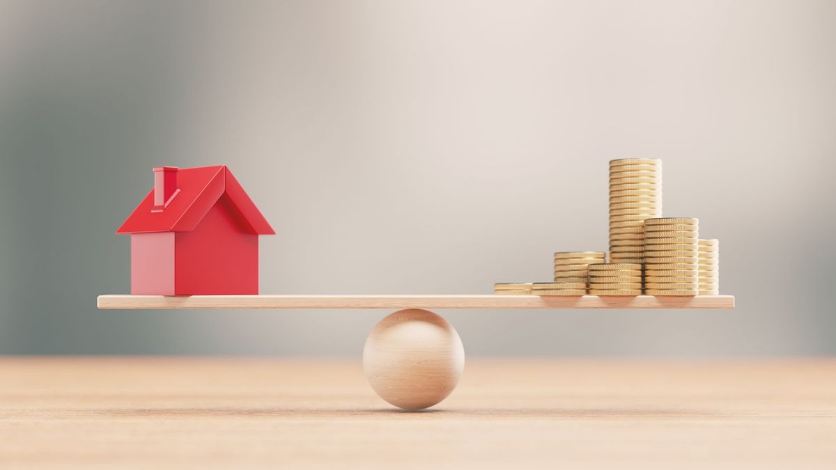 Домик и деньги лежат на импровизированных весах