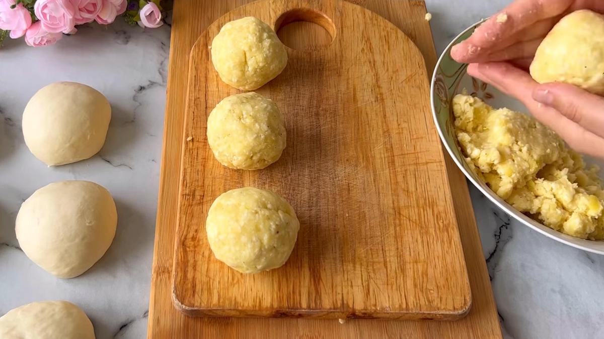 На разделочной доске шарики картофельно-сырной начинки. Ряжом шарики теста