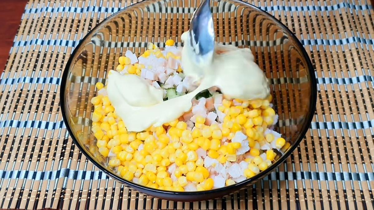 В миске для салата курица, огурец, кукуруза, к которым добавляют майонез
