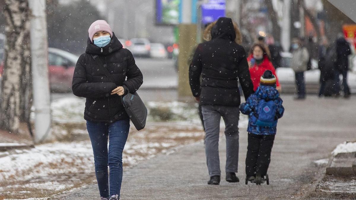 Девушка в маске идет по городу