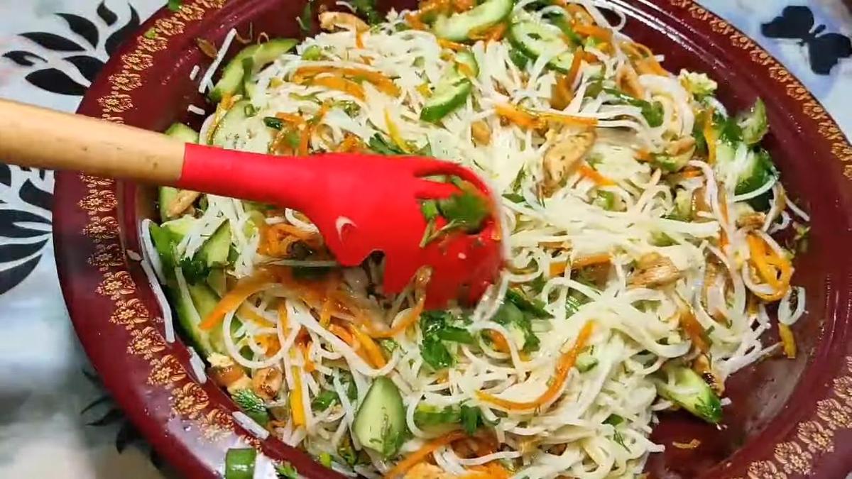 Смешивание салата с фунчозой, курицами, морковью и огурцами