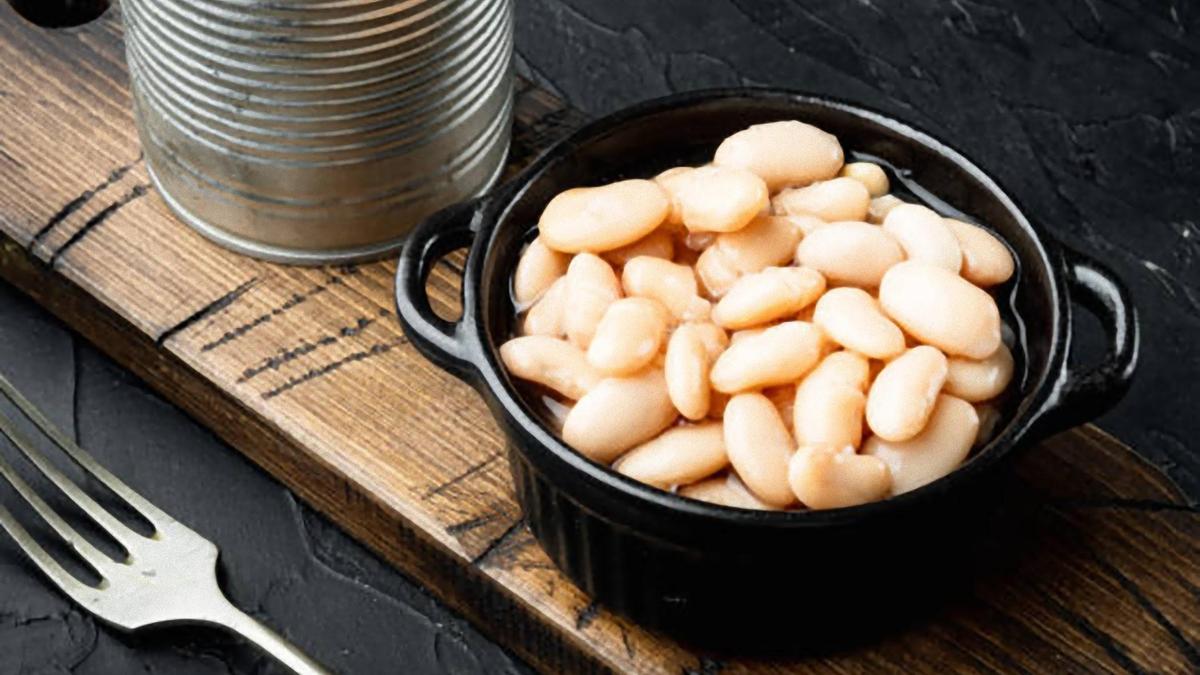 Фасоль в миске, вилка, жестяная банка