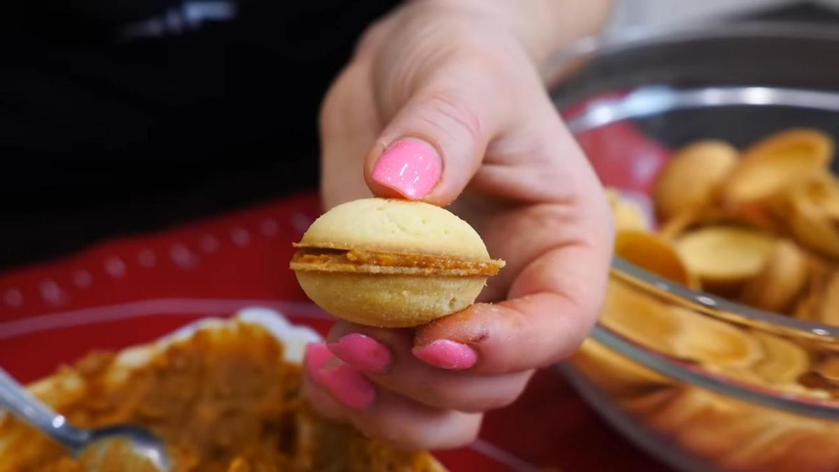 Девушка держит в руках готовый орешек со сгущенкой