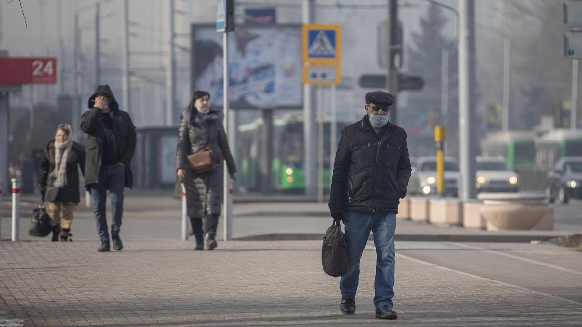 Люди в масках и теплой одежде идут по улице