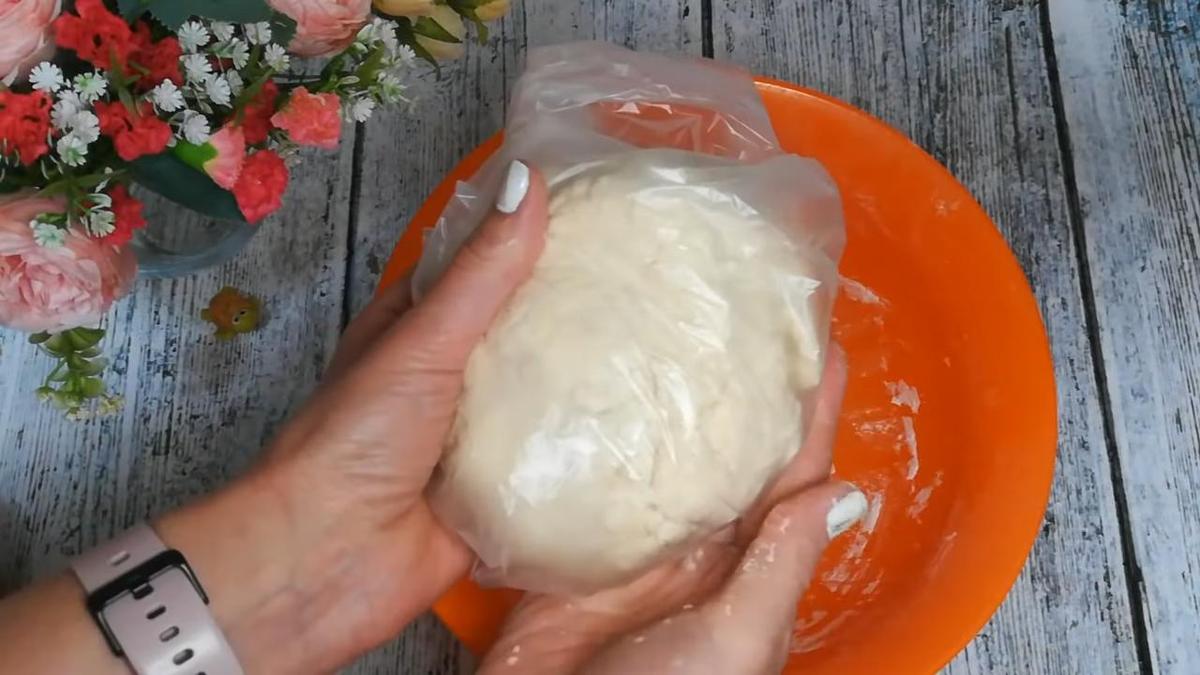 В женских руках тесто, завернутое в полиэтилен