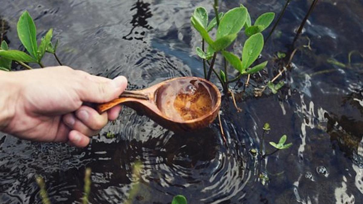 рука с ковшом черпает воду из водоема