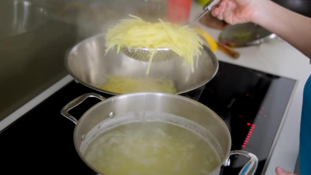 Отваренный картофель шумовкой достают из кастрюли