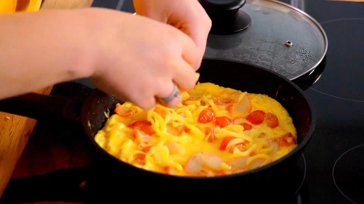 В сковороду с омлетом насыпают тертый сыр