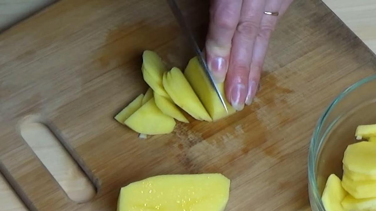 На разделочной доске нарезают очищенный картофель