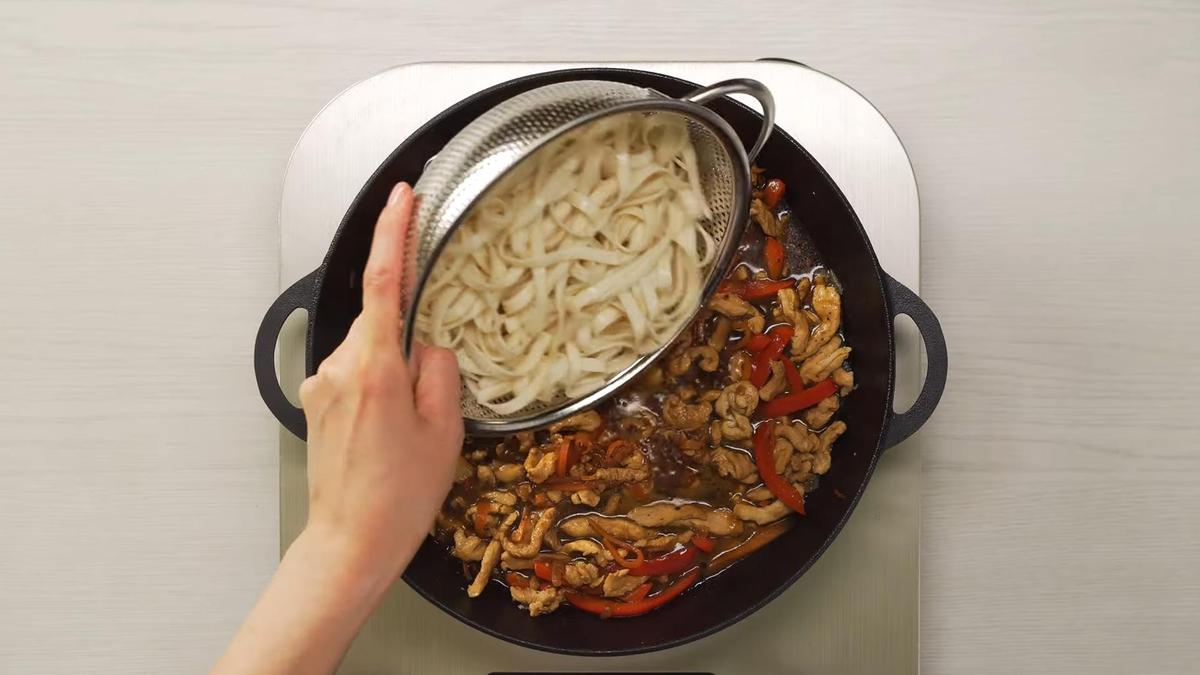 Лапшу из дуршлага перекладывают в сковороду с курицей и овощами