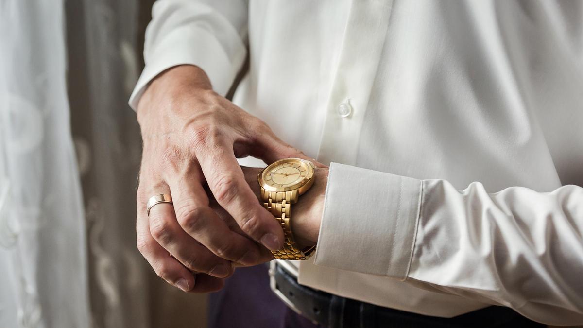Мужчина в белой рубашке надевает часы