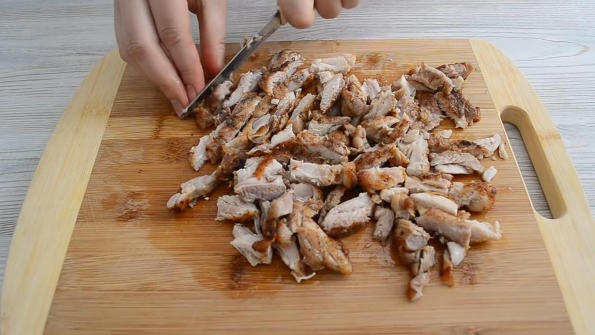 Обжаренную курицу нарезают на разделочной доске