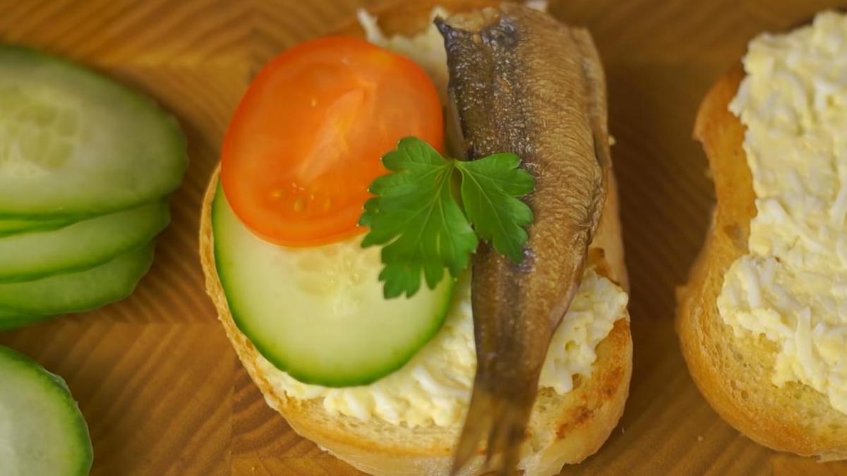 На батон уложены огурец, томат и шпрота