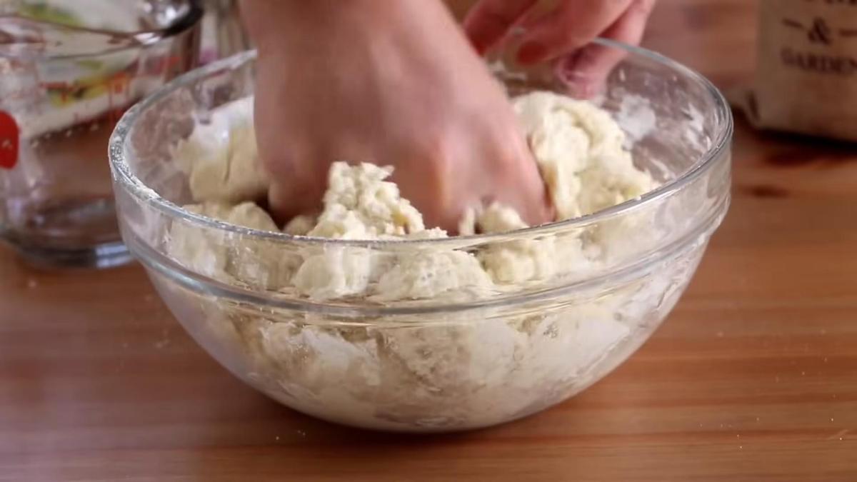 В стеклянной миске рукой вымешивают тесто для пиццы