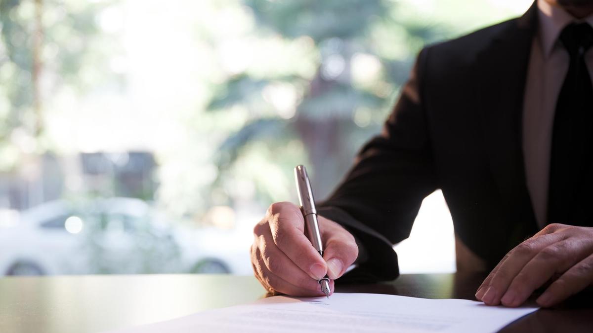 Мужчина ставит подпись в бумагах
