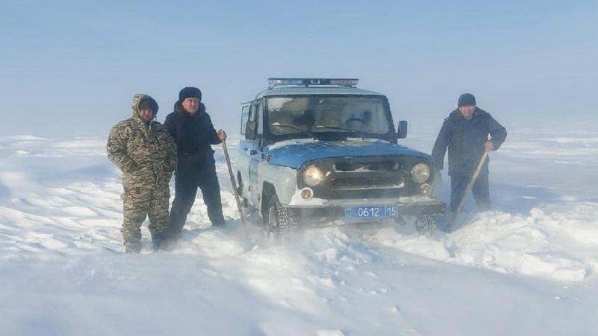 Полицейские стоят рядом с машиной в буран в СКО