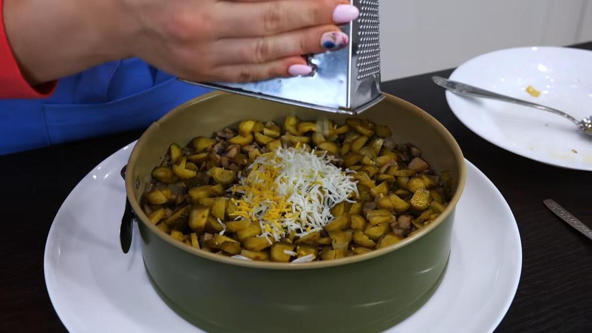 В руках у девушки терка, на которую трут отваренные куриные яйца