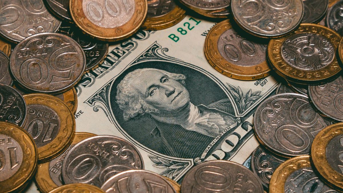 Монеты тенге лежат на купюре доллара