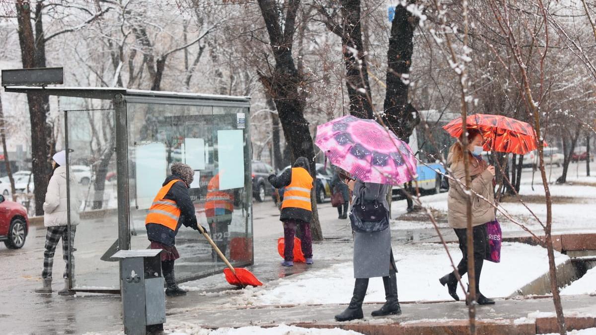 Люди идут по улице под снегом