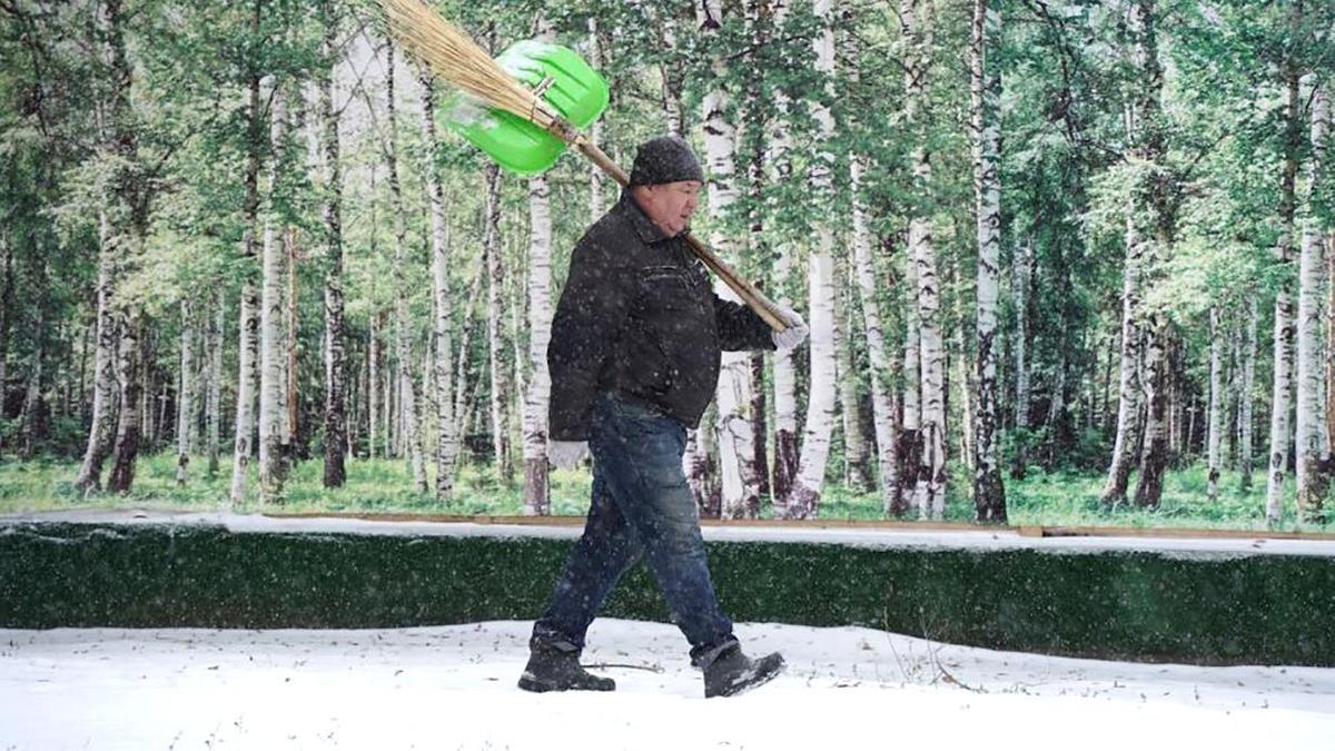 Дворник идет с метлой и совком за спиной