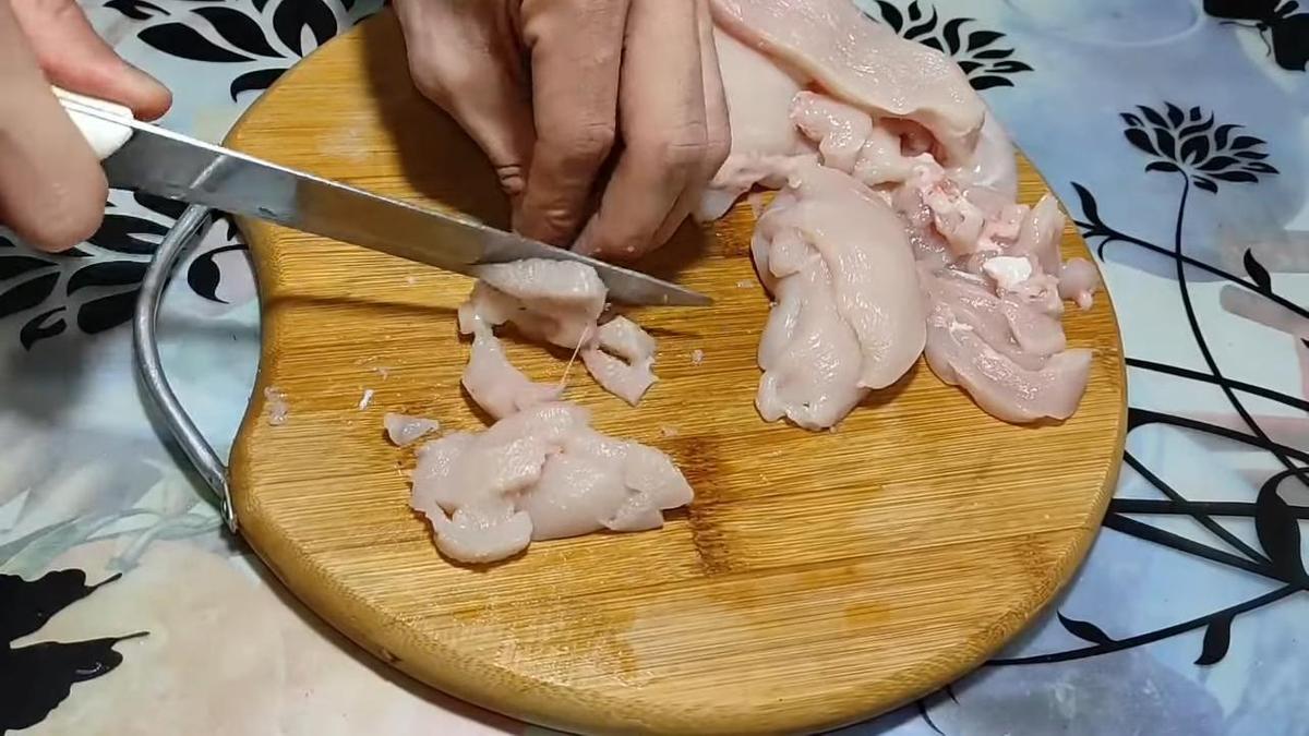 На разделочной доске нарезают филе курицы