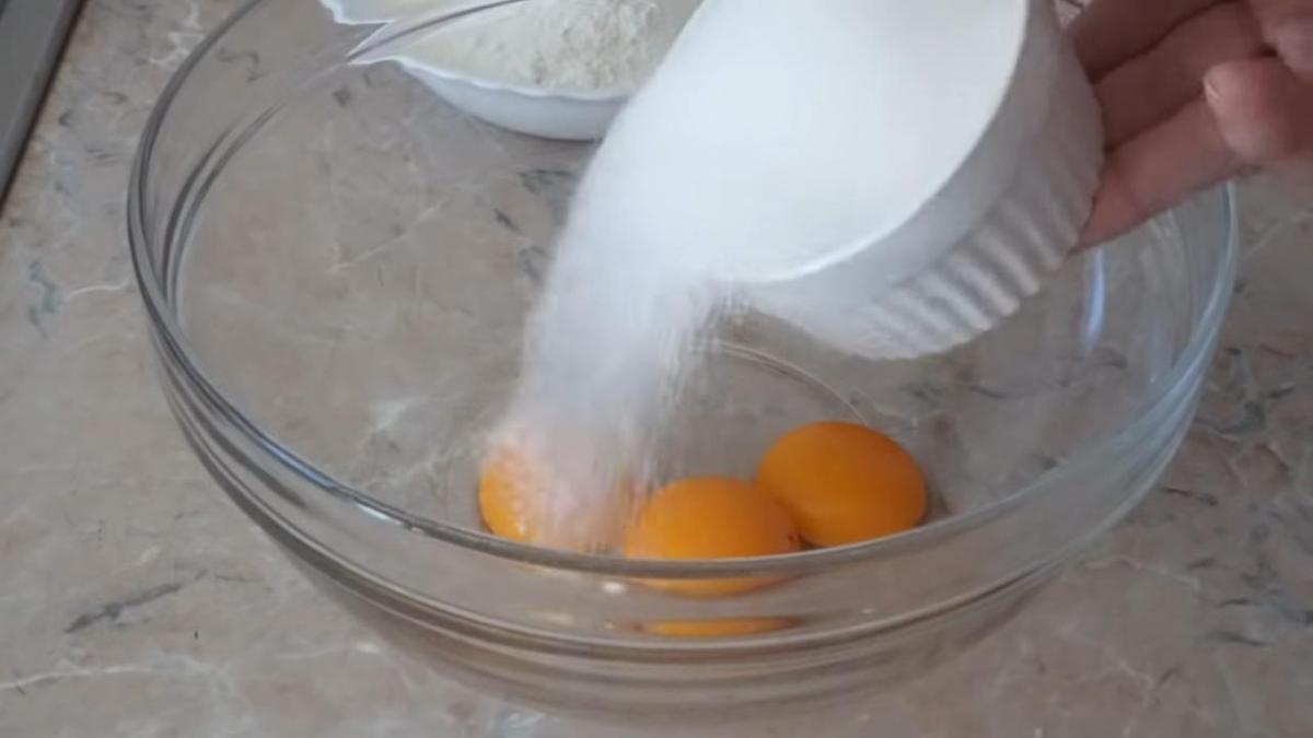 Добавление сахара в стеклянную емкость с желтками