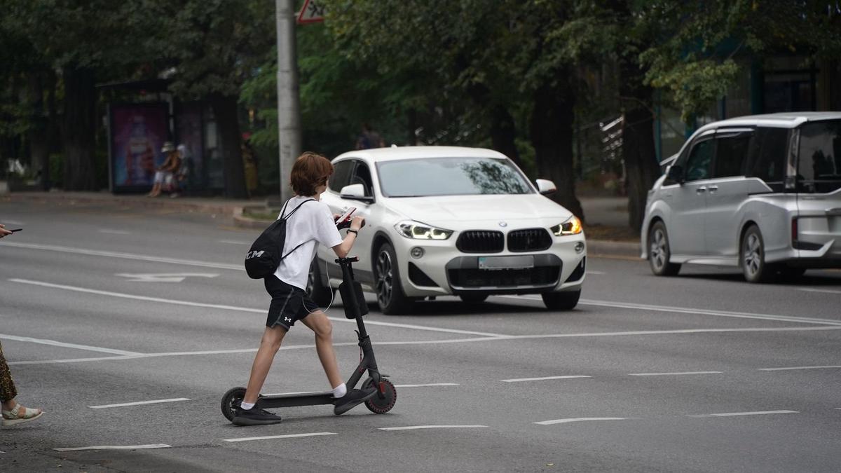 Самокат теуіп бара жатқан жасөспірім