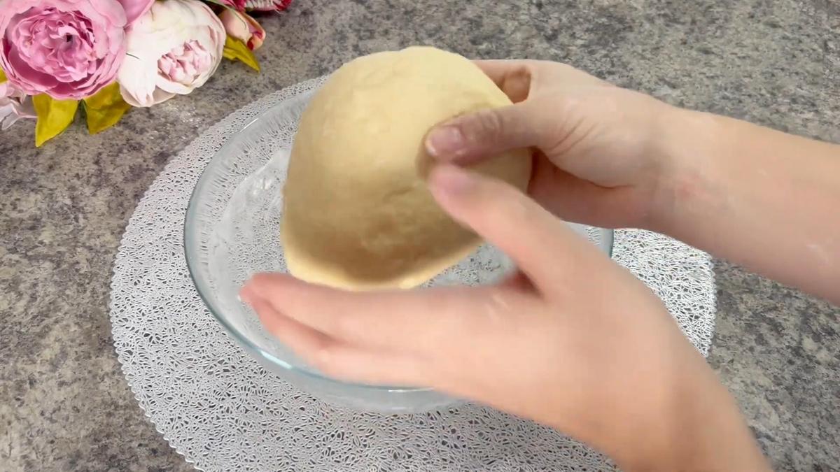 Девушка держит в руках вымешанное тесто
