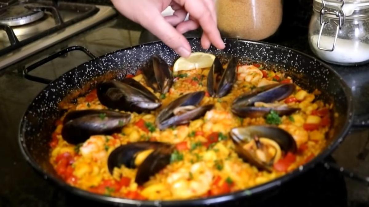 В сковороду к паэлье с морепродуктами добавляют дольки лимона