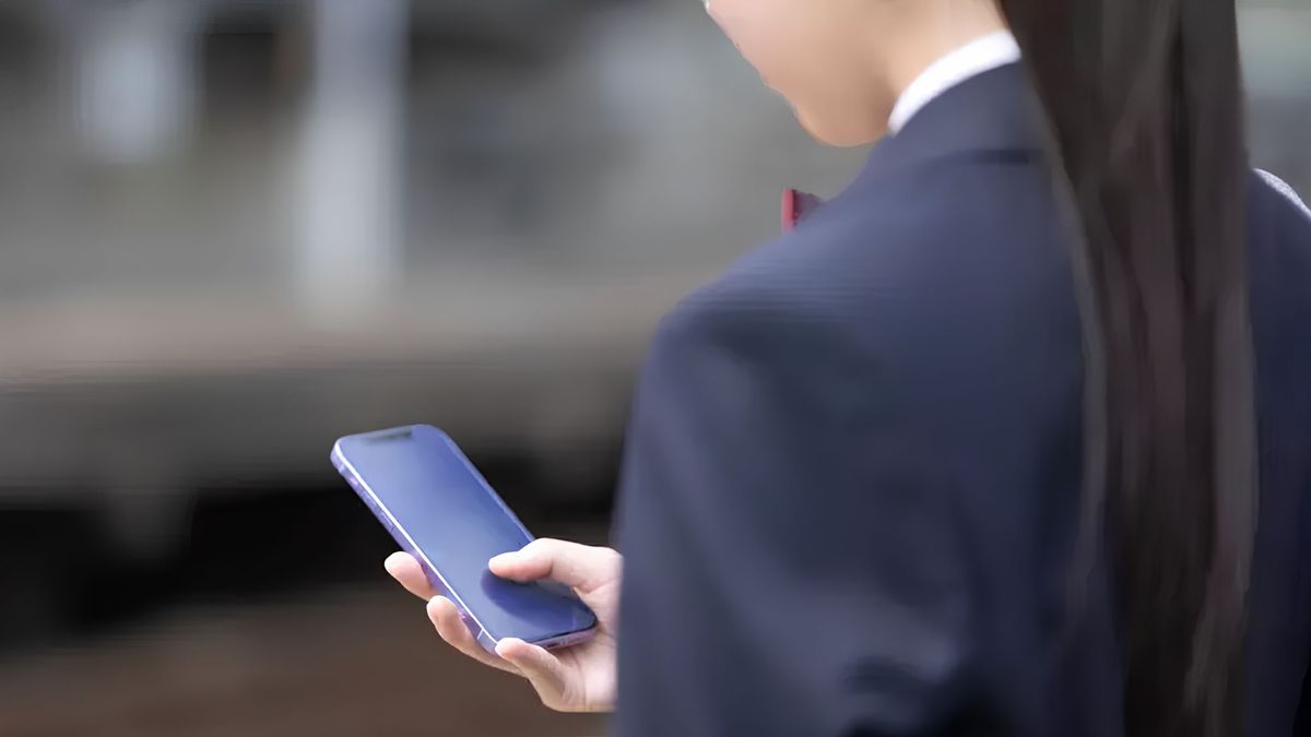 Телефон ұстап тұрған оқушы