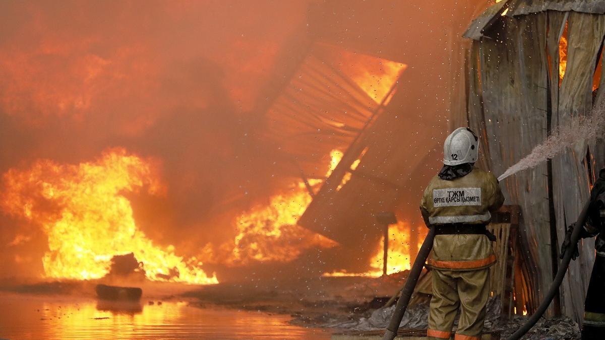 пожарный тушит полыхающее здание