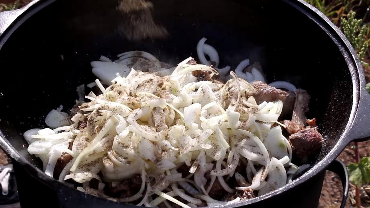 К ребрышкам и субпродуктам добавьте нарезанный кольцами лук, соль и черный перец