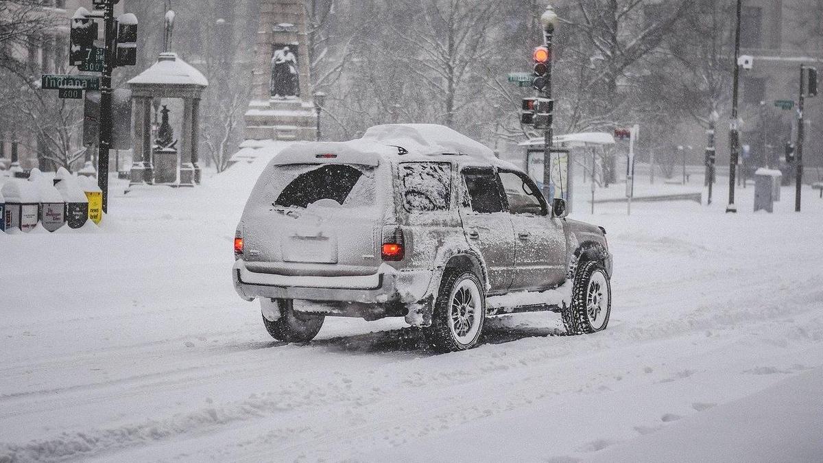 Заснеженный автомобиль едет по дороге