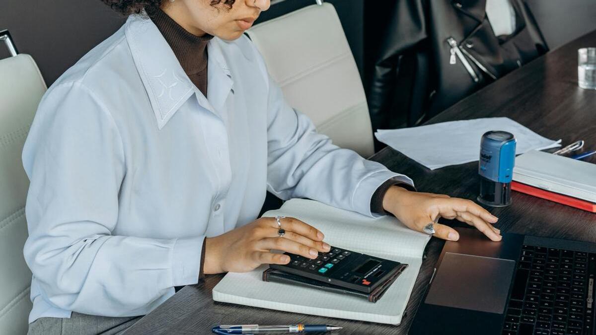 Девушка считает на калькуляторе и вводит данные в компьютер