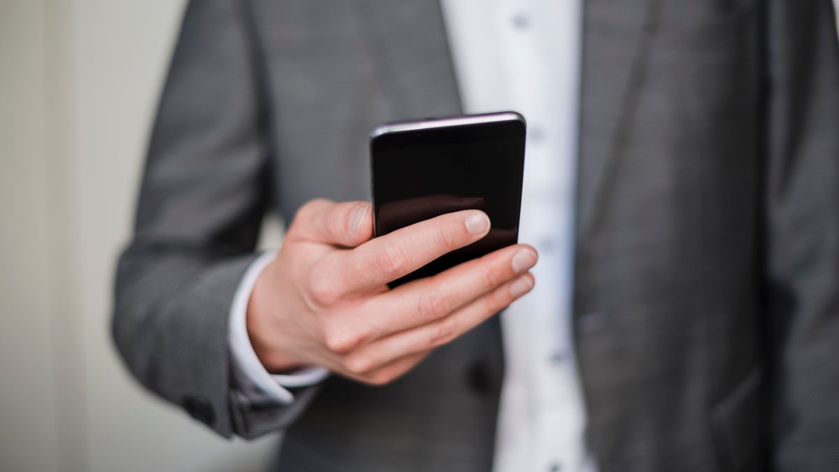 Мужчина в костюме держит смартфон