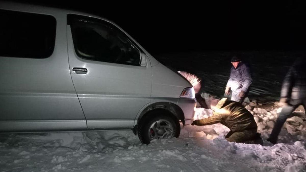 Мужчины пытаются вызволить застрявшее в снегу авто Мужчины пытаются вызволить застрявшее в снегу авто