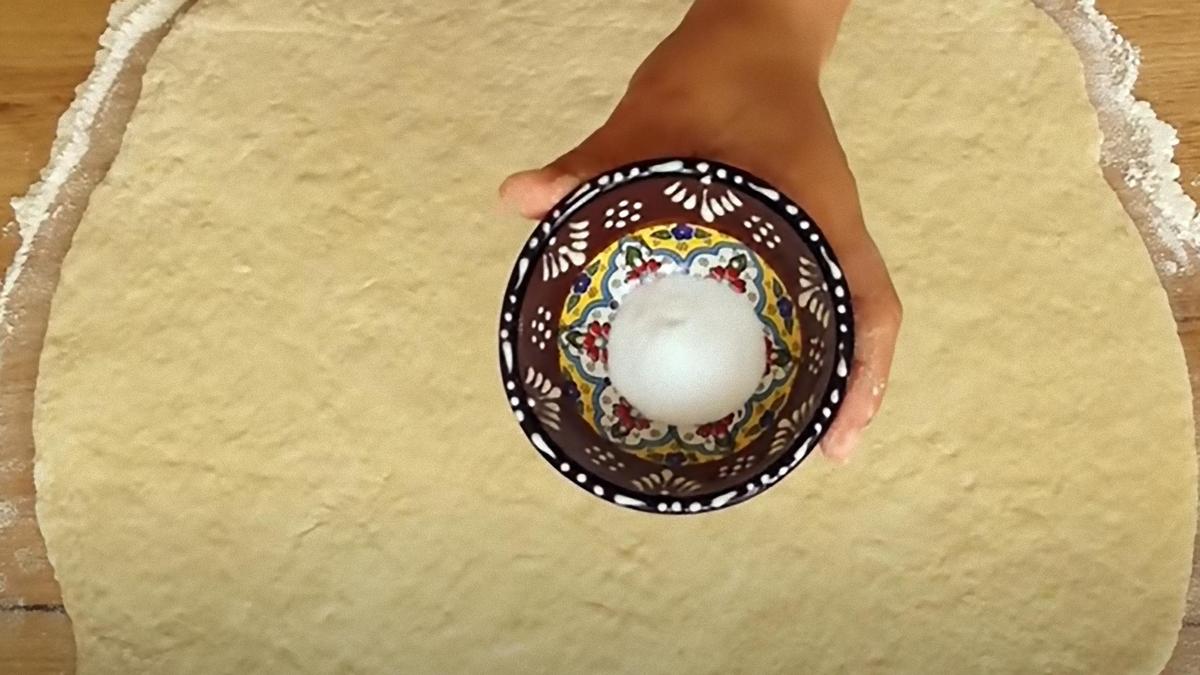 В креманке держат соду над раскатанным пластом теста