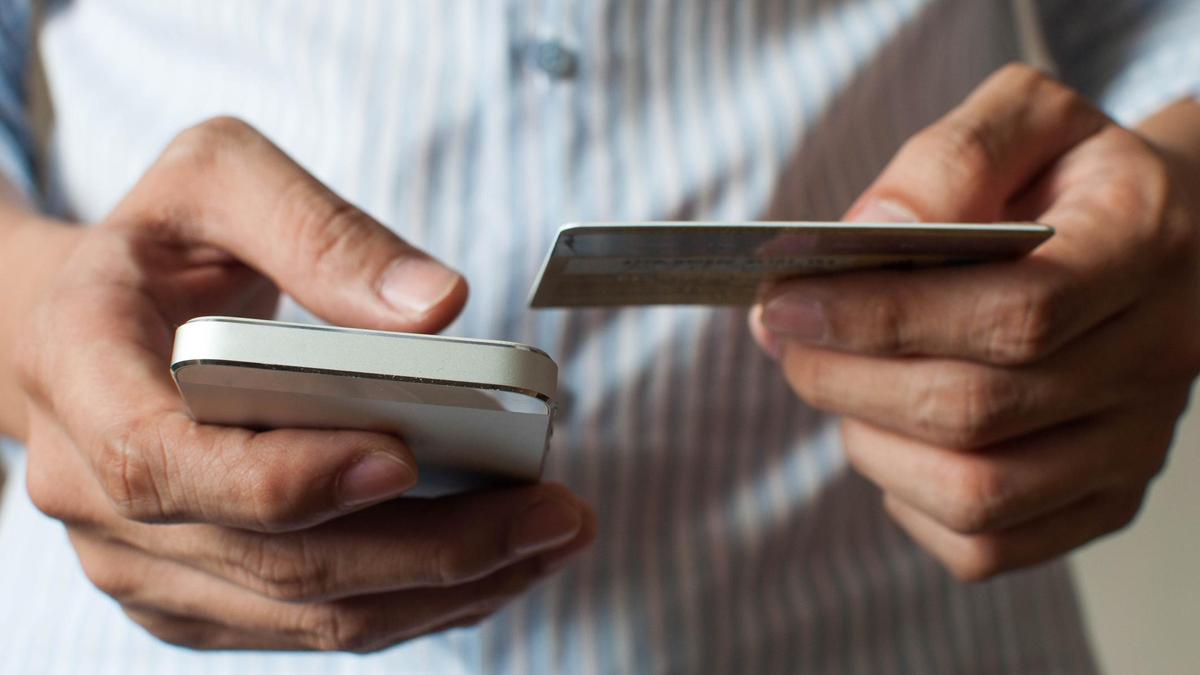Смартфон және банк картасын ұстап тұрған жігіт Смартфон және банк картасын ұстап тұрған жігіт