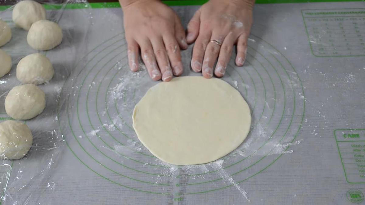 На столе раскатанная лепешка из теста