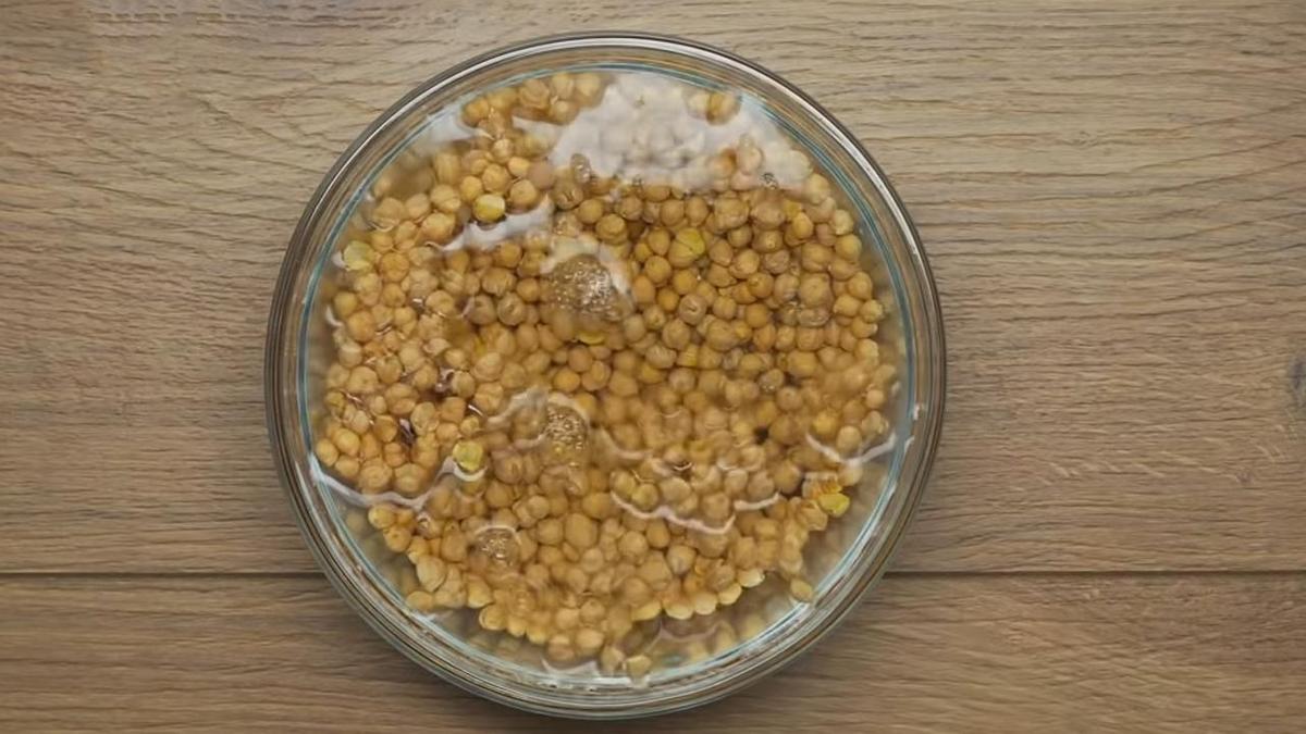 Горох нут залит водой в стеклянной миске