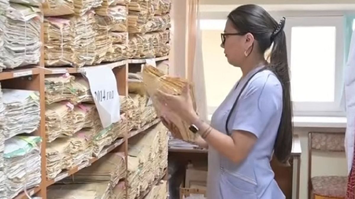 Работница роддома изучает архив
