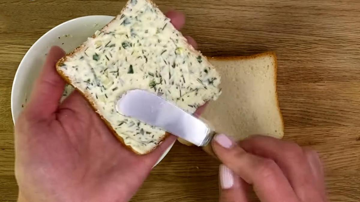 Кусок тостового хлеба намазывают сливочным маслом с чесноком и зеленью