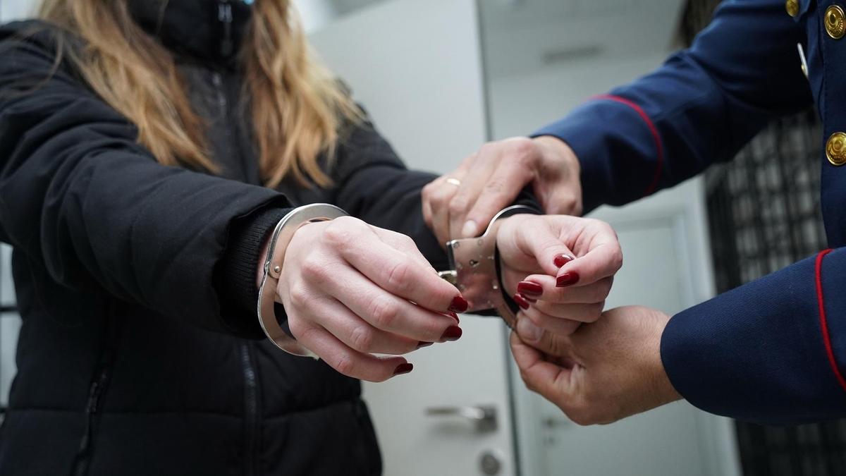 Полиция әйелдің қолына кісен салуда Полиция әйелдің қолына кісен салуда