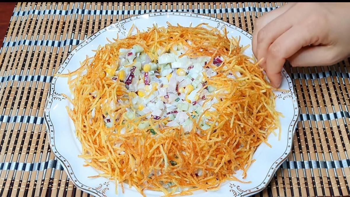 Салат выложен горкой на блюдо. Его обсыпают обжаренным картофелем